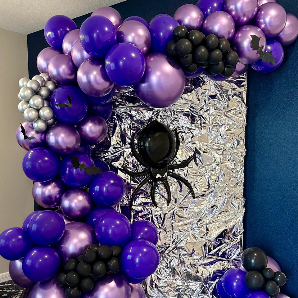 Party for Wednesday wednesday themed install with an organic garland in black, silver, and purples, a specialty spider balloon, and bat accents