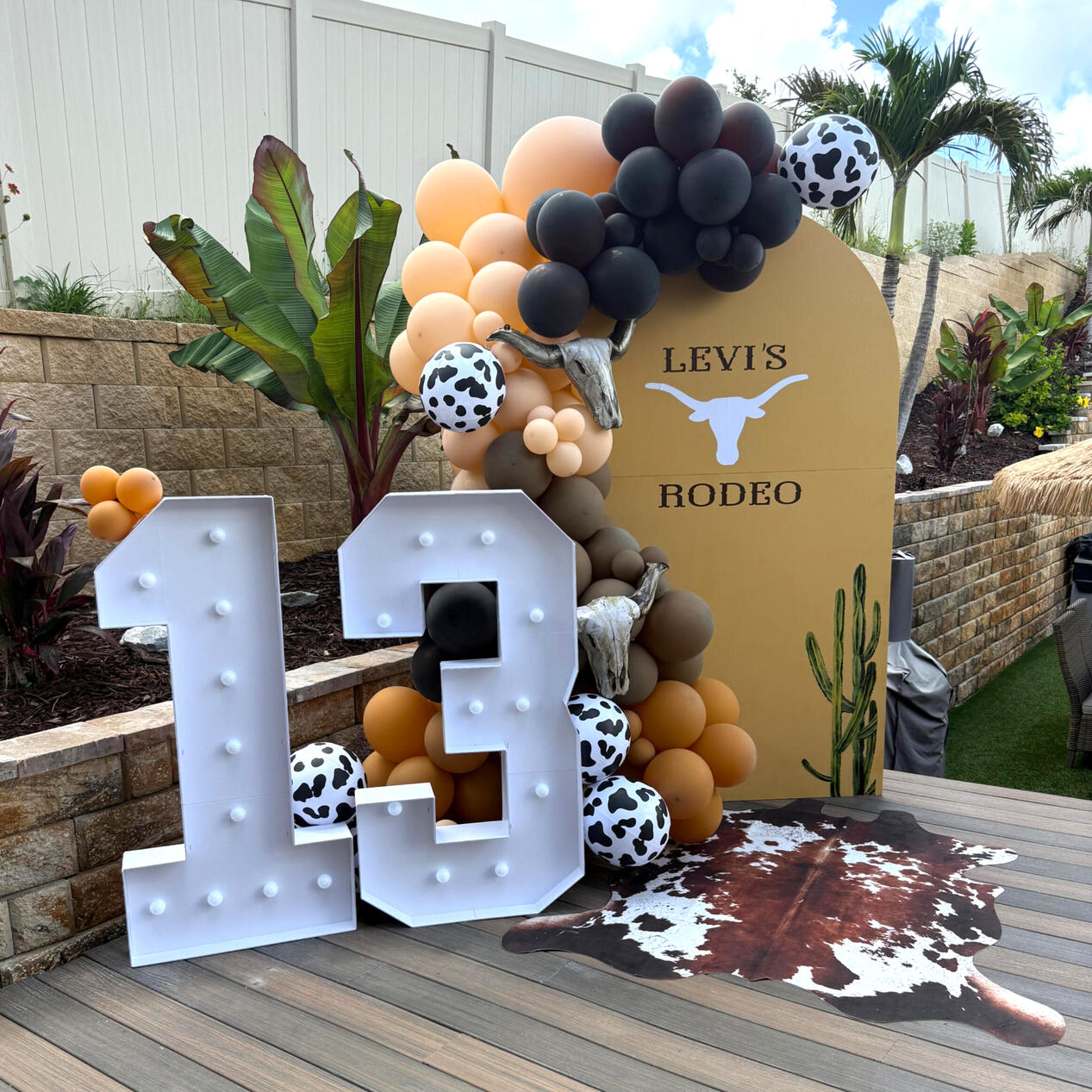 Party at the Rodeo rodeo themed party set up with arches, organic balloon garland, and marquee numbers. | Minneola, FL